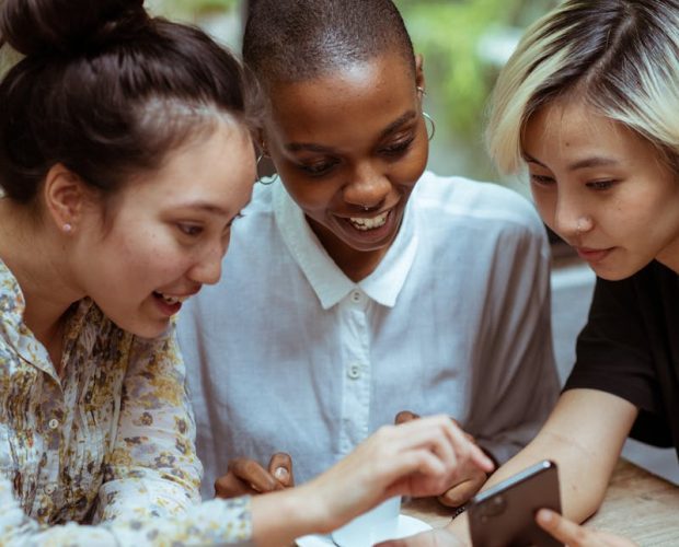 Cheerful multiethnic women browsing smartphone